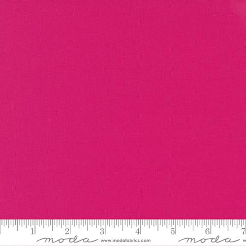 Solid pink fabric swatch with a ruler at the bottom for scale.