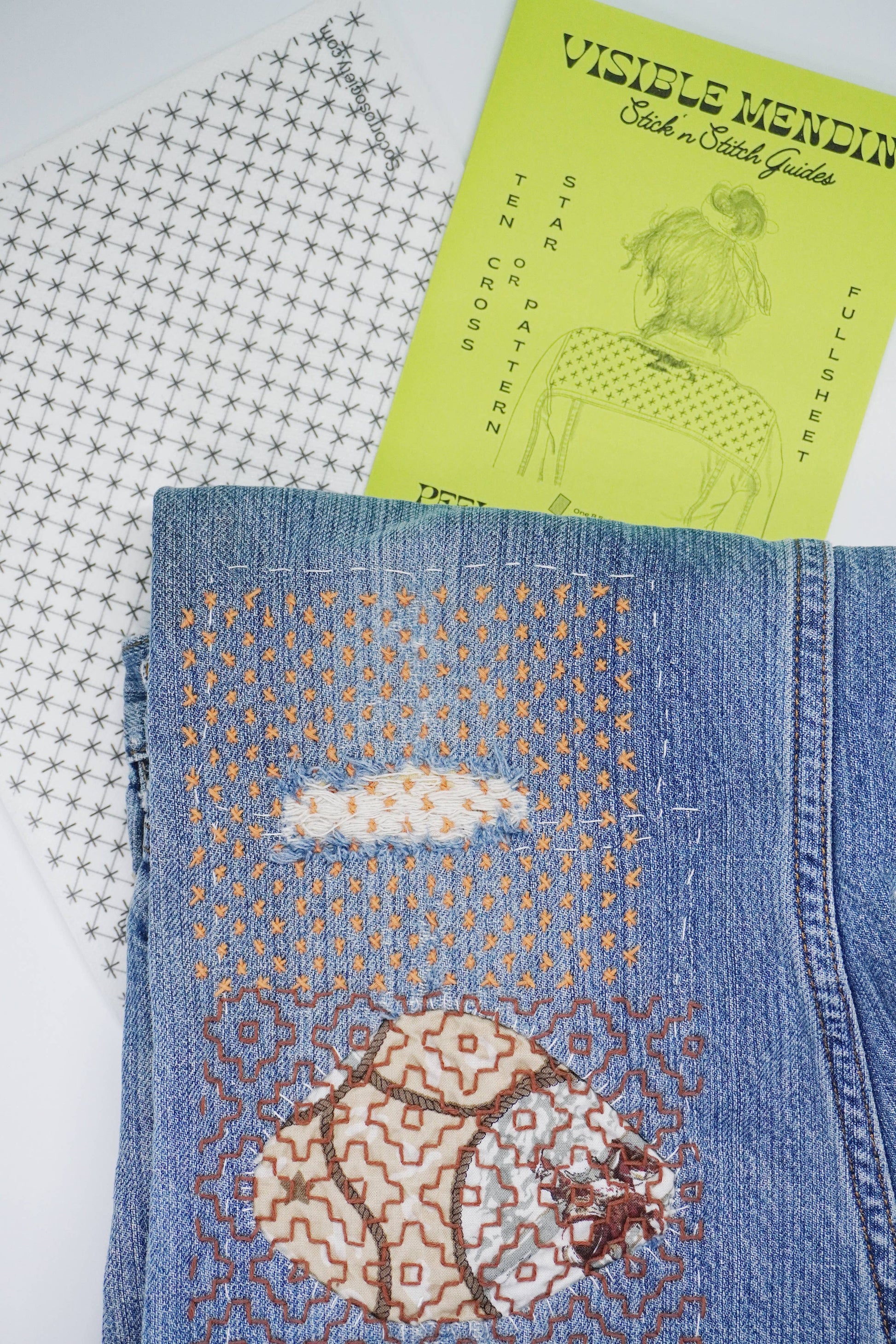 Blue denim fabric with embroidered bear design, next to a green pattern sheet titled 'Visible Mendin'.