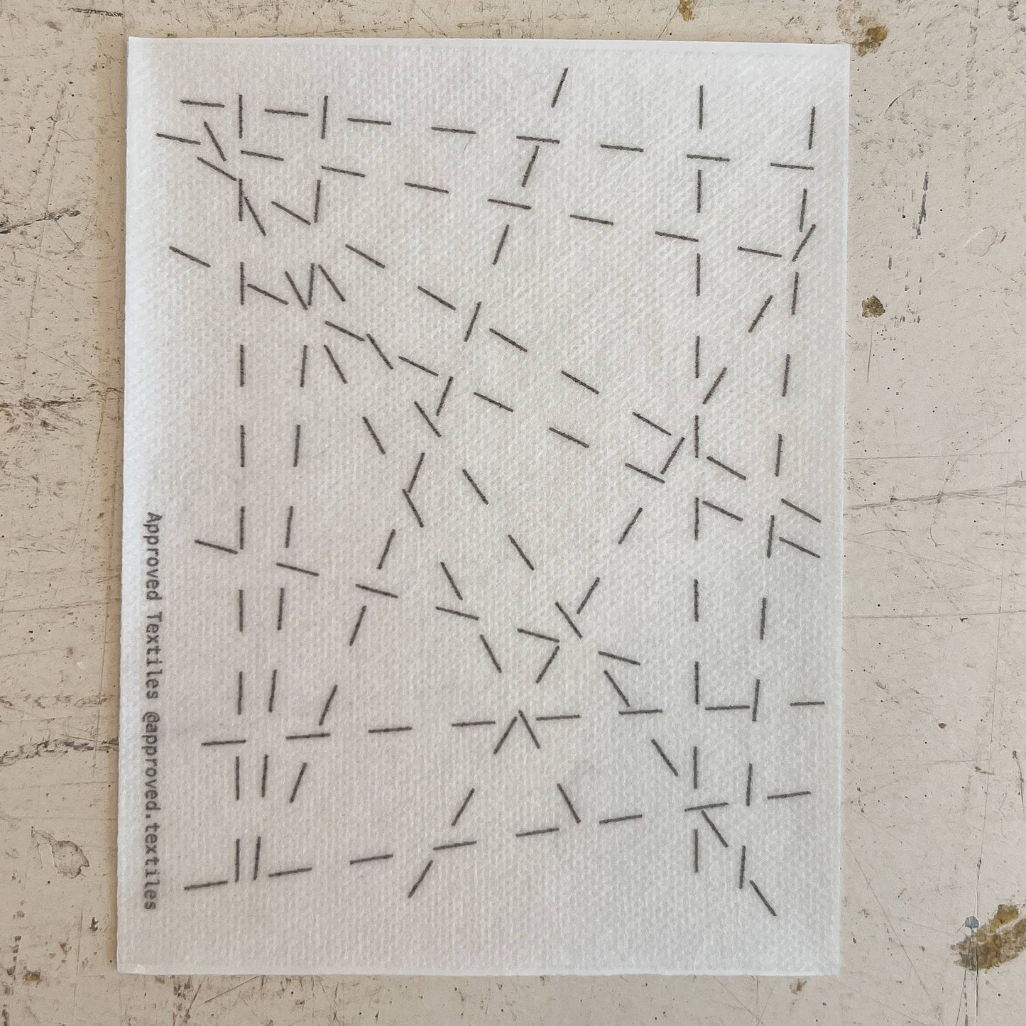 White cloth with black geometric pattern on a textured beige surface
