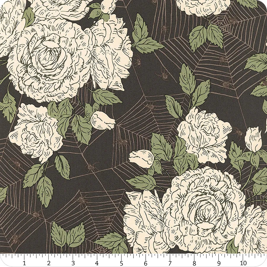Floral pattern with roses and leaves on a black background with spider webs, ruler at the bottom for scale.